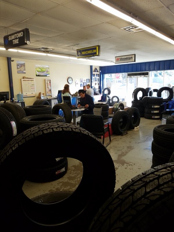Busy service area with tire inventory and customers at the counter